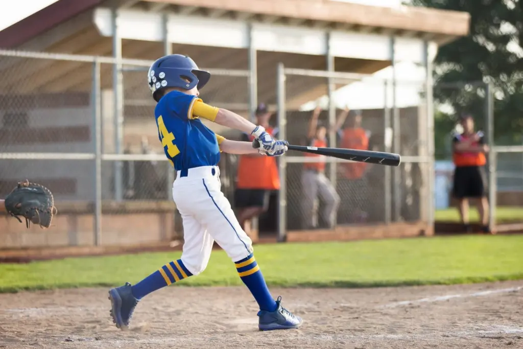 A young baseball player in a blue and yellow uniform swinging the bat during a game