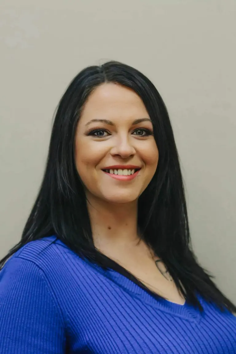 Danielle, who runs the front desk, smiling, with long dark hair and a royal blue top