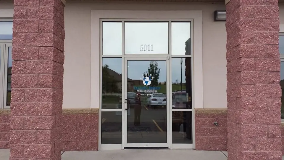 The office's glass front door, with 5011 above it and the practice's logo on the glass, between two rose-coloured brick pillars